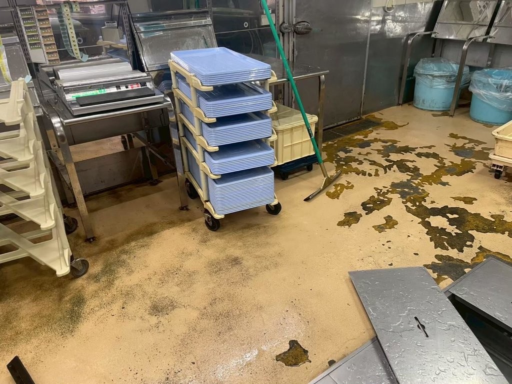 埼玉県朝霞市のスーパーマーケット鮮魚作業室で、剥がれた既存塗床をダイヤ研磨で下地処理している様子